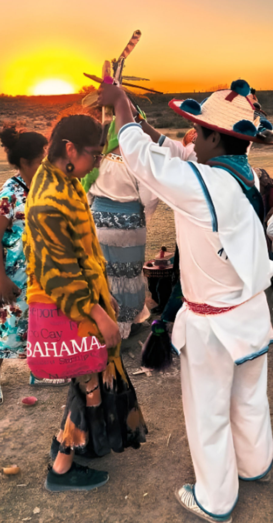 Two people in traditional clothing embracing during a cultural celebration, surrounded by others.